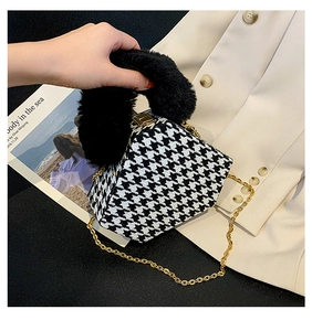 Detail of houndstooth crossbody bag with black faux fur handle and gold chain strap