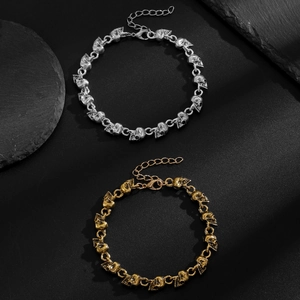Close-up van gotische schedelarmbanden in zilveren en gouden afwerking op zwarte achtergrond