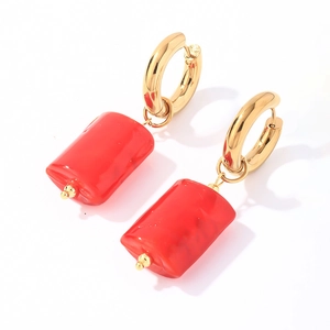 Detailed macro view of golden stainless steel hoops with red stone cylinder charms