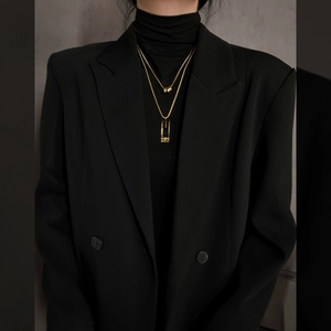 Close-up of double-layered gold titanium steel necklace with geometric pendants on a model
