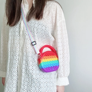 Girl wearing rainbow heart pop it crossbody bag with adjustable rainbow strap on white shirt