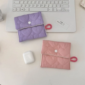 Detailed view of quilted purple and pink sanitary bags with heart patterns on a white desk