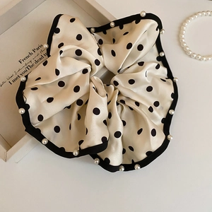 Macro detail of polka dot satin scrunchie with lace edge and white imitation pearls