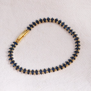 Macro shot of gold tennis bracelet with navy blue marquise cut crystals and clasp