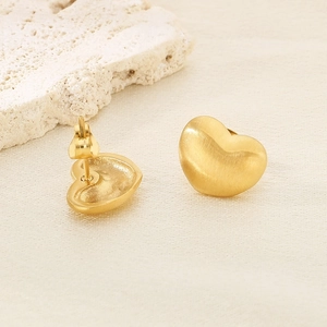 Détail de boucles d'oreilles cœur doré avec finition brossée sur soie et pierre