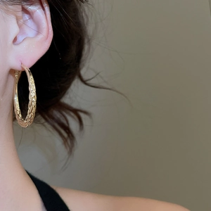 Detail of gold twisted hoop earrings showing woven texture and polished metallic finish