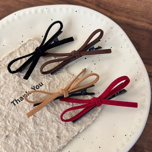 Set of four velvet bow hair clips in red black and brown on a ceramic tray