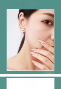 Macro shot of silver X-shaped sterling silver earrings with diamonds on model ear