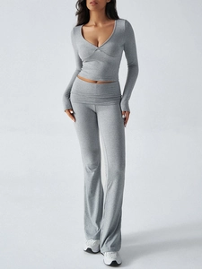 Detail of grey knitted two-piece set featuring a V-neck long sleeve top and flared trousers