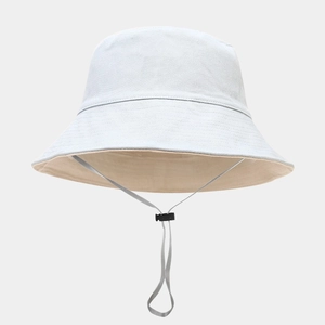 Detail of a foldable bucket hat showing two-tone canvas fabric and adjustable wind strap