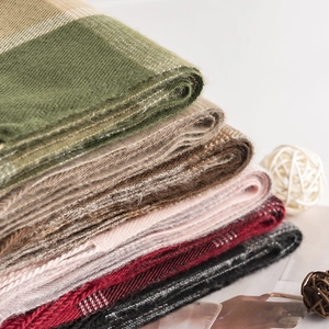 Close-up of thick plaid scarves in olive, khaki, and burgundy soft cashmere-like fabric
