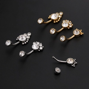 Detailed view of silver and gold belly rings with clear zircon stones on black backdrop
