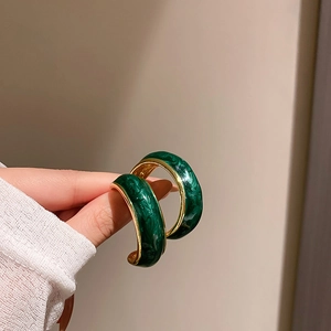 Detailed close-up of C-shaped dark green marble earring with elegant gold trim edges