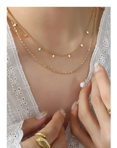 Close-up of double-layered gold chain necklace with geometric diamond-shaped pendants