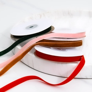 Velvet ribbon rolls in dark green, pink, brown, and red on a white marble tray