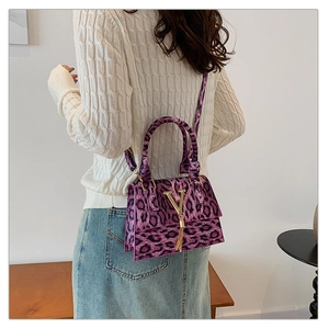 Dettaglio borsa leopardata viola con logo a V dorato e nappina metallica pendente