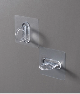 Detail of transparent self-adhesive ring hooks for curtain rods on a gray wall