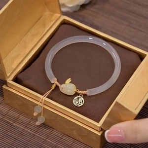 Macro shot of a purple jade-textured bracelet with gold rabbit charm in a gift box