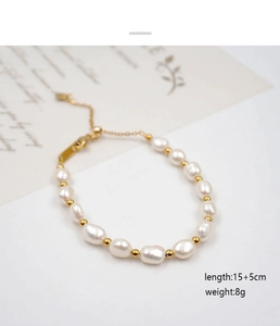 Dettaglio del bracciale regolabile con perle d'acqua dolce, sfere dorate e chiusura a moschettone