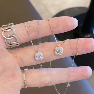 Macro view of square halo diamond necklaces and layered silver rings for women