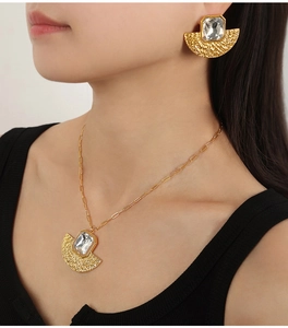 Elegant gold fan-shaped necklace and earrings set with crystal stones on a model