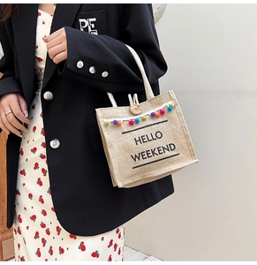Detail of linen handbag with rainbow pom-poms, wood button, and Hello Weekend print