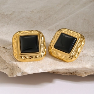 Macro shot of square black gemstone earrings with textured gold plating on stone
