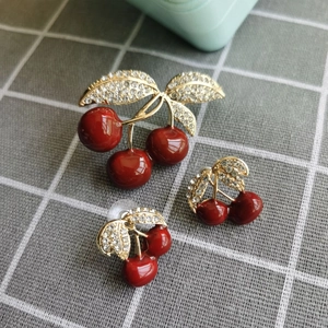Ensemble broche et boucles d'oreilles cerise en émail rouge avec feuilles dorées