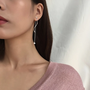 Detail of silver long wave tassel threader earrings with sleek curved line and bead