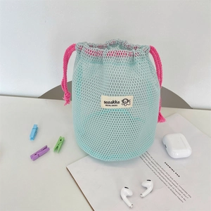 Close-up of mint green mesh drawstring pouch with pink cords and stylish brand label