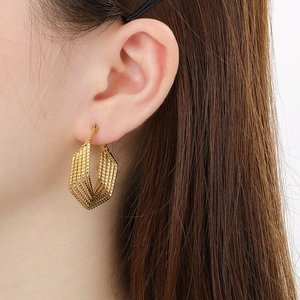 Detailed view of irregular geometric golden earrings with a hollow honeycomb pattern