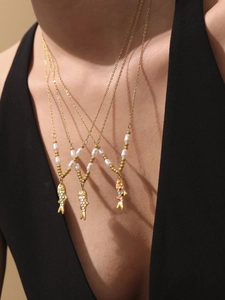 Detail of layered gold necklaces featuring colorful enamel koi fish pendants and white pearls