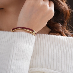 Close-up of double-layered gold bracelet with zircon cross on model in white sweater