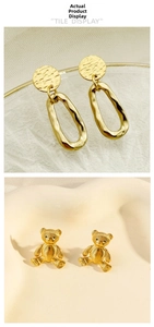 Detail of geometric hammered oval drop earrings and textured gold bear studs