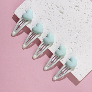 Close-up of five mint green heart-shaped hair clips on a white stone background