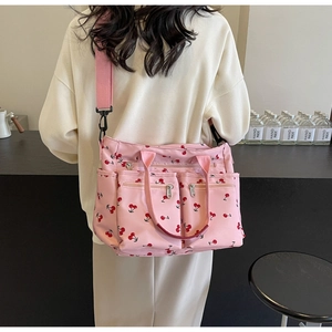 Pink cherry print tote bag with multiple pockets and adjustable shoulder strap worn by model