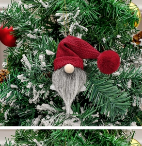 Close-up of a Christmas gnome ornament with red knit hat and grey beard on a tree