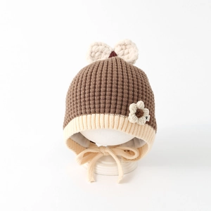 Detail of baby knitted hat showing brown waffle texture and handmade floral accent