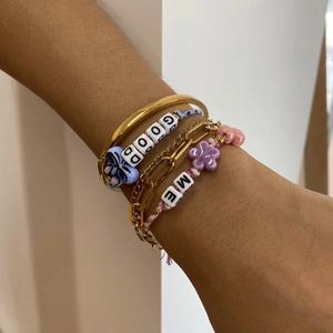 Detail of layered jewelry set with gold bangles and colorful resin flower bead bracelets