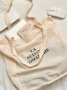 Minimalist beige canvas tote bag with black LA SUISINE OMACHE print and long shoulder straps