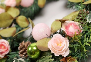 Detailed close-up of pink silk roses and decorative glossy ornaments on the Christmas wreath