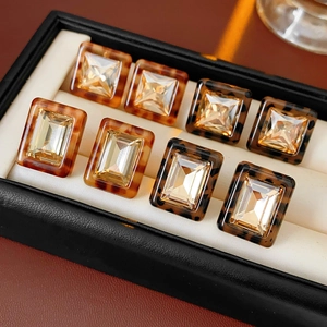 Macro shot of 8 square tortoiseshell resin earrings with faceted crystals in a box
