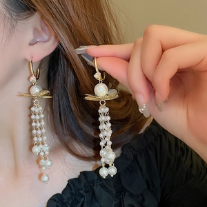Détail de boucles d'oreilles longues à pampilles perles et finitions dorées sur modèle