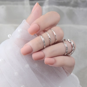 Dettaglio di set anelli argento con unghie finte rosa opaco su pizzo bianco
