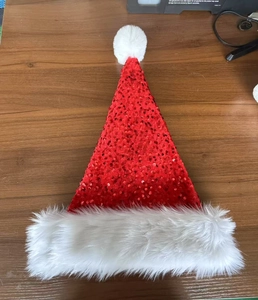 Detail of red sequined Christmas hat with white plush fur trim and fluffy pompom on top