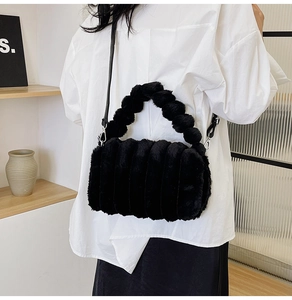 Detail of black plush handbag with unique fuzzy ball strap on white shirt