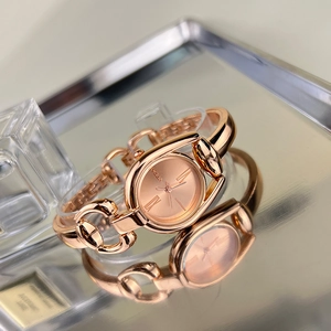 Detail of rose gold vintage quartz watch on a silver tray with clear reflection