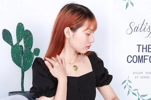 Golden titanium steel necklace with circular patterned pendant shown on a female model