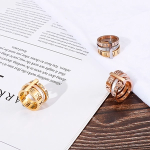 Three-color stainless steel rings with Roman numerals and crystals on wood background