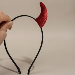 Close-up of red glitter devil horns on a black plastic headband for Halloween party